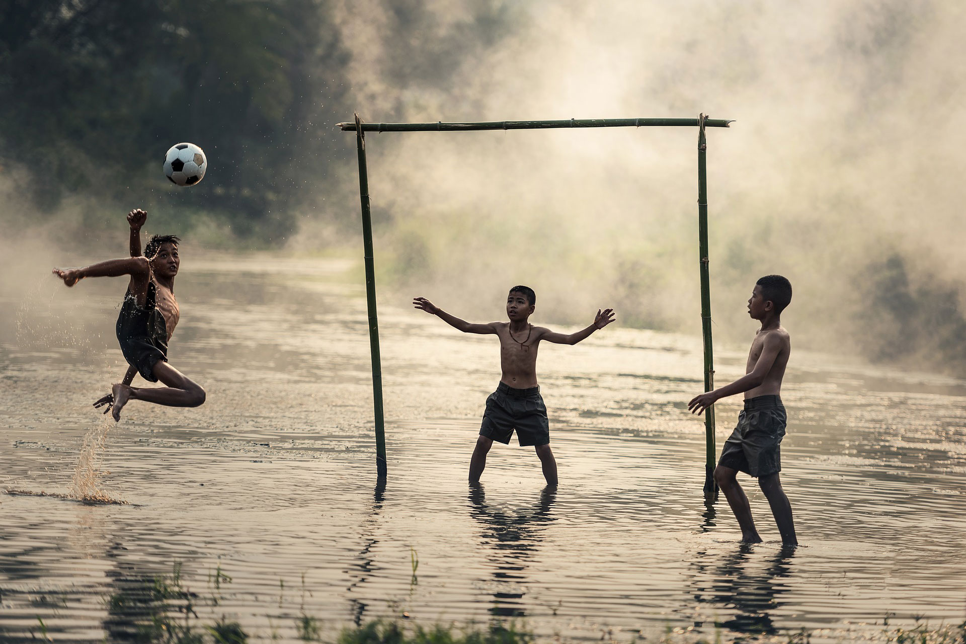 Kinder beim Fußballspiel auf knöchelhoch überschwemmtem Platz