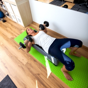 Fitnesstrainerin Bernadette Hörner demonstriert die Übung Bankdrücken mit Kurzhanteln auf Step liegend