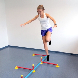 Sportlerin beim einbeinigen Hopsen über Hürden in der innsbrucker Praxis "Gelenkpunkt"