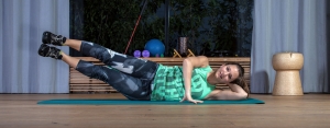 Fitnesstrainerin Bernadette Hörner demonstriert eine Übung "Beine heben in Seitlage" für die seitlichen Bauchmuskeln