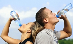 Mann und Frau trinken aus Wasserflasche