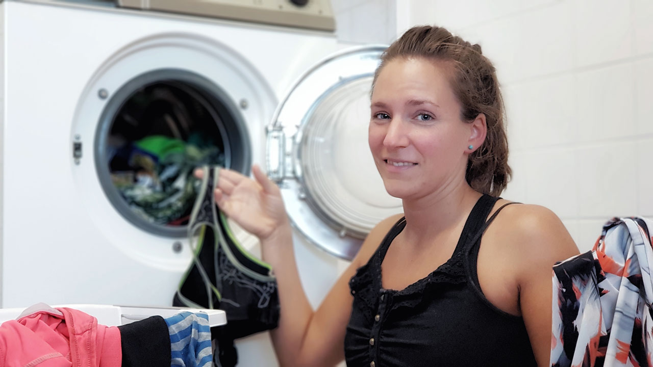 Fitnessbloggerin Bernadette Hörner mit Schmutzwäsche vor der Waschmaschine